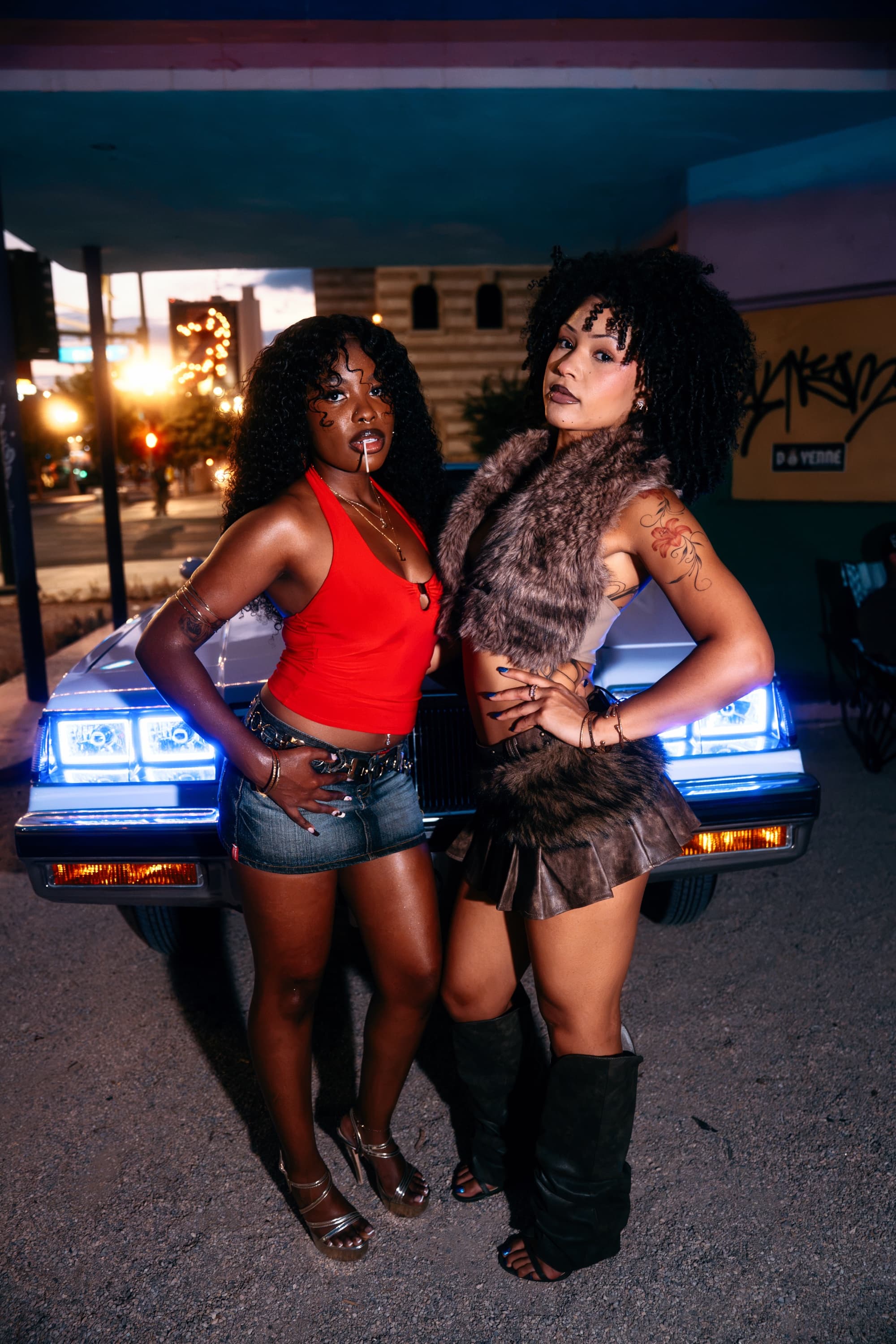 Two models in front of a white Buick Regal with glowing blue halo headlights under a vintage canopy