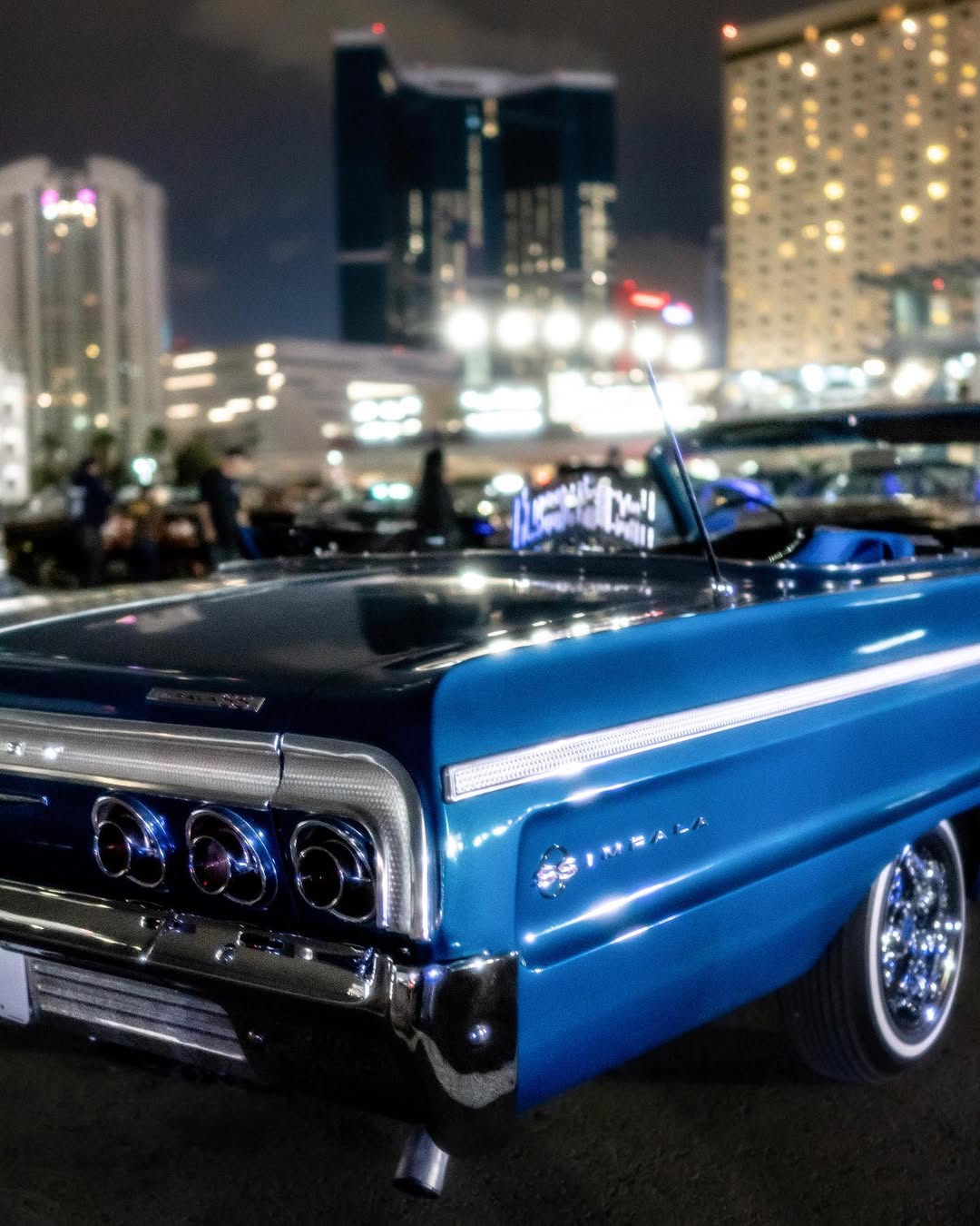 Blue Chevrolet Impala lowrider cruising through Las Vegas city lights at night