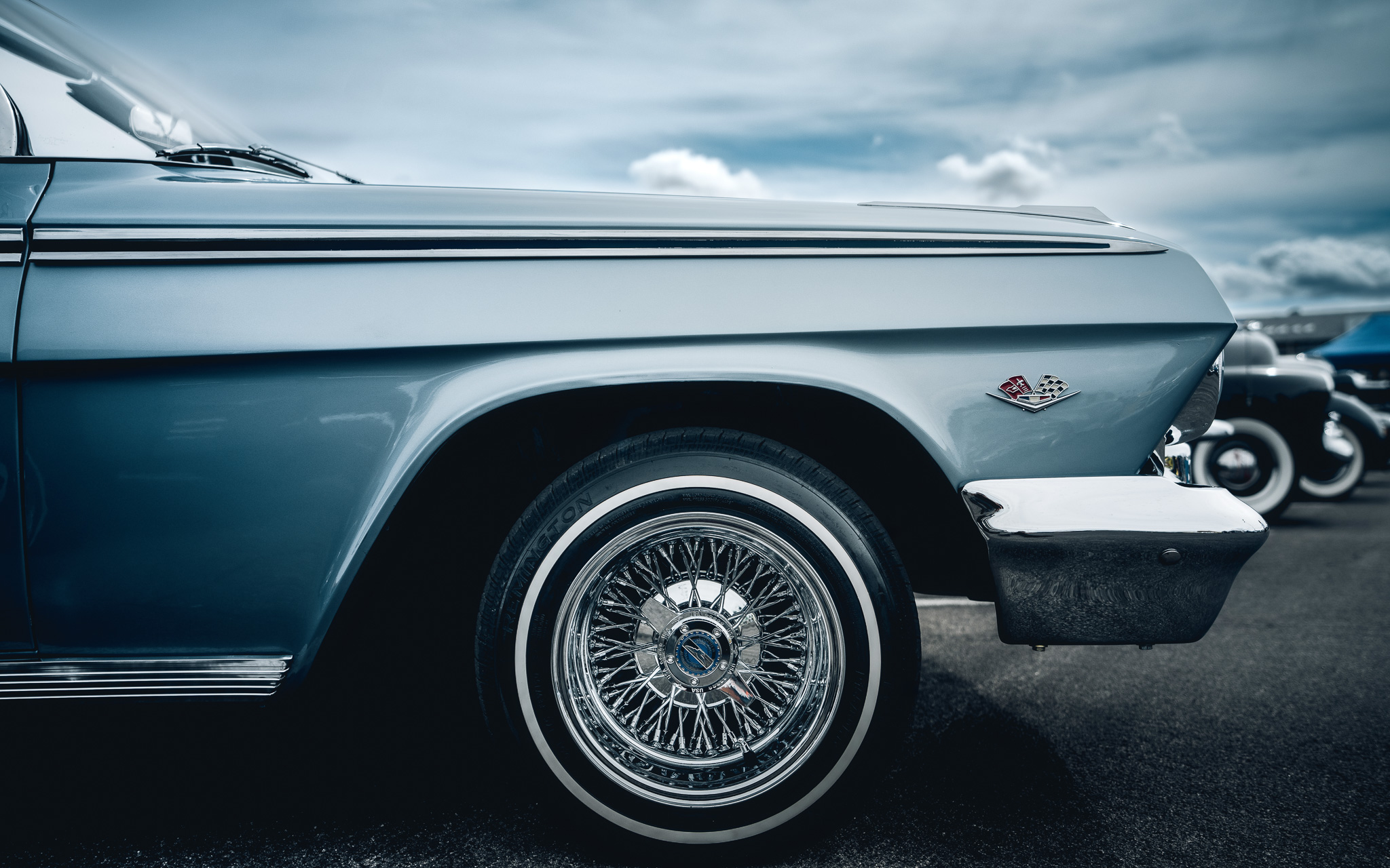 Classic chrome wire wheel detail shot against dramatic cloudy sky