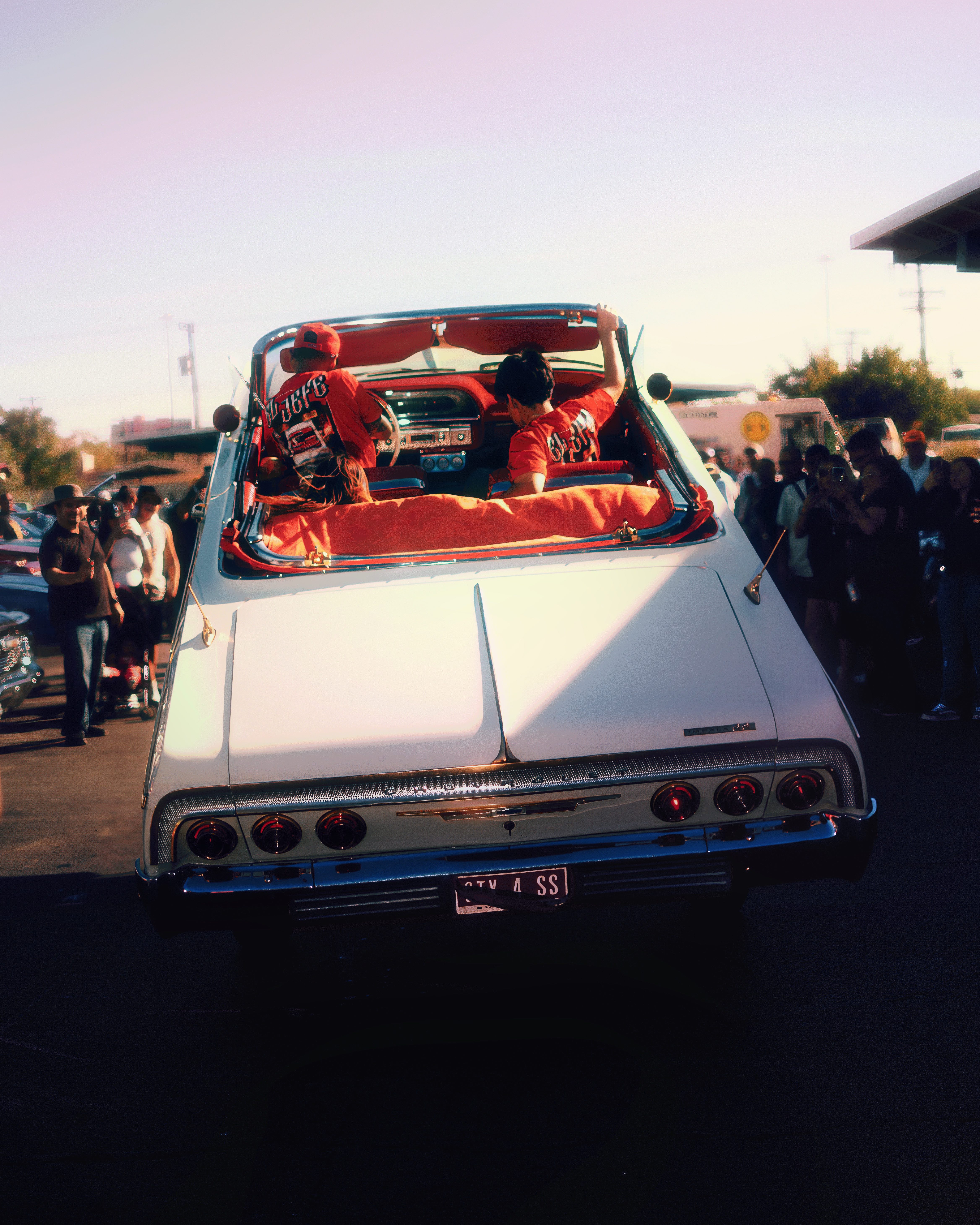 White Impala convertible at golden hour car show with red interior and custom details