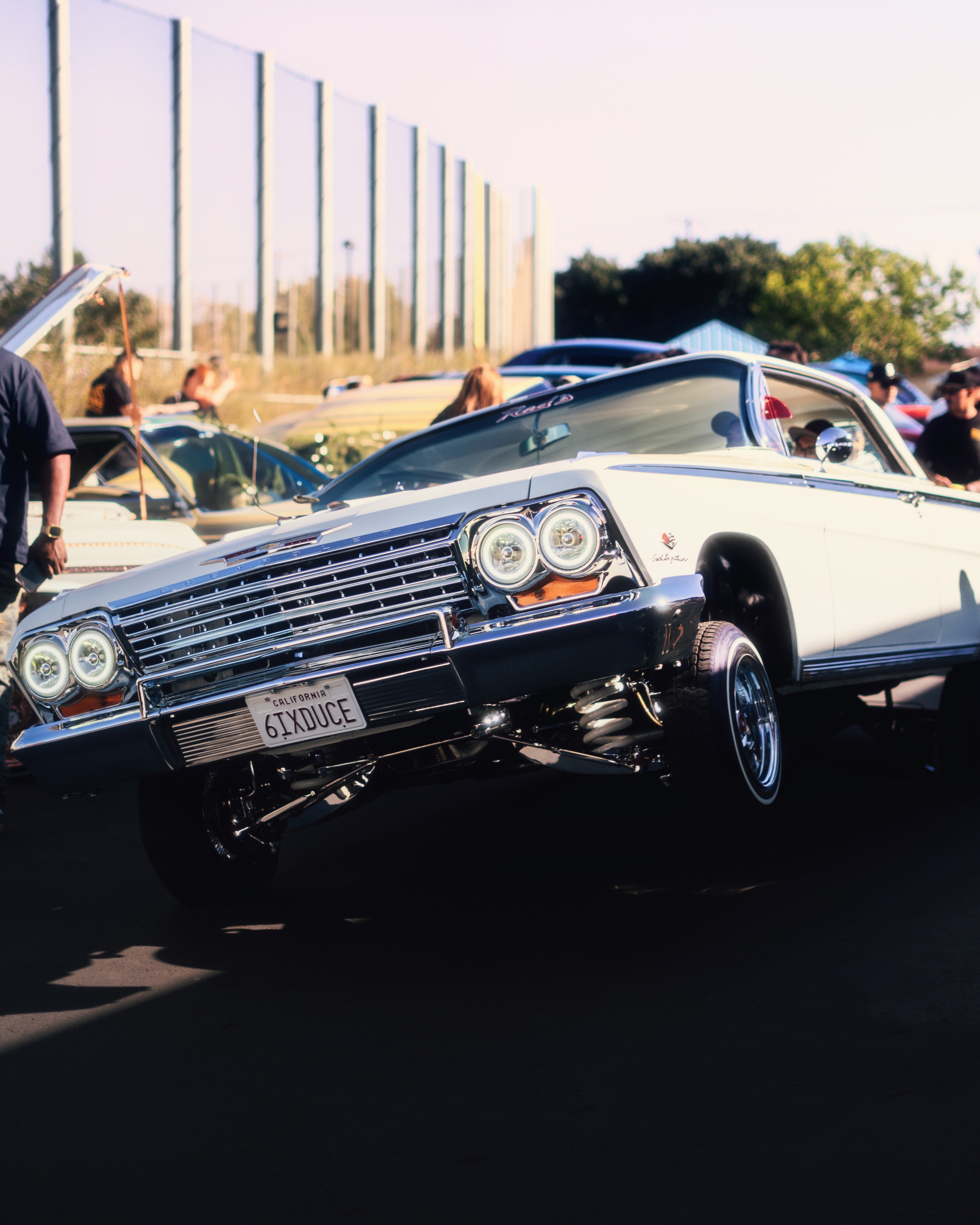 Classic white Impala lowrider front view at car show with chrome details